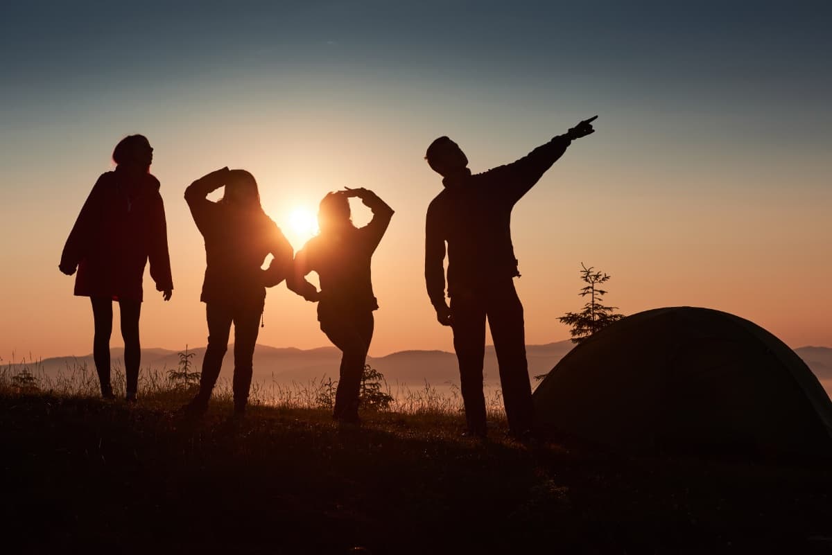 Team auf Berggipfel bei Sonnenuntergang – symbolisiert gemeinsame Ziele und Teamarbeit