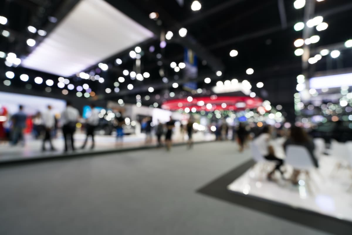 Messekommunikation mit KI vorbereiten – Messehalle mit Bokeh-Lichtern